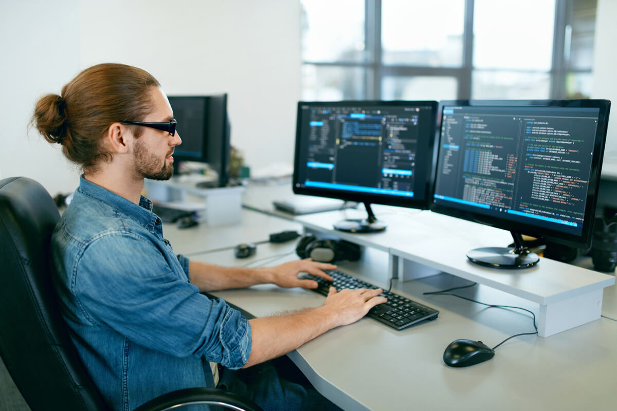 programmierer vor zwei monitoren am arbeiten