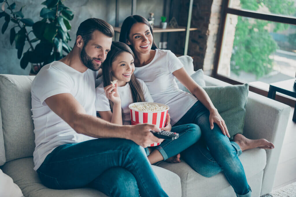 eltern mit kin auf der couch beim fernsehen