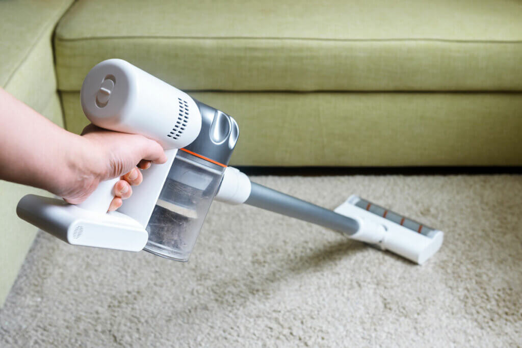 Person saugt Teppich mit 2-in-1-Staubsauger