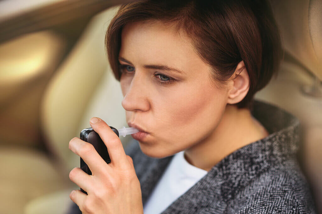 junge frau pustet in alkoholtester