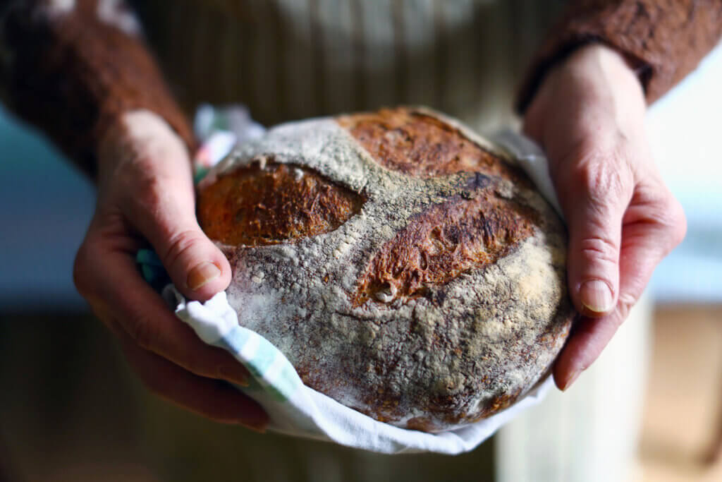 person haelt krustenbrot in der hand, fokus brot