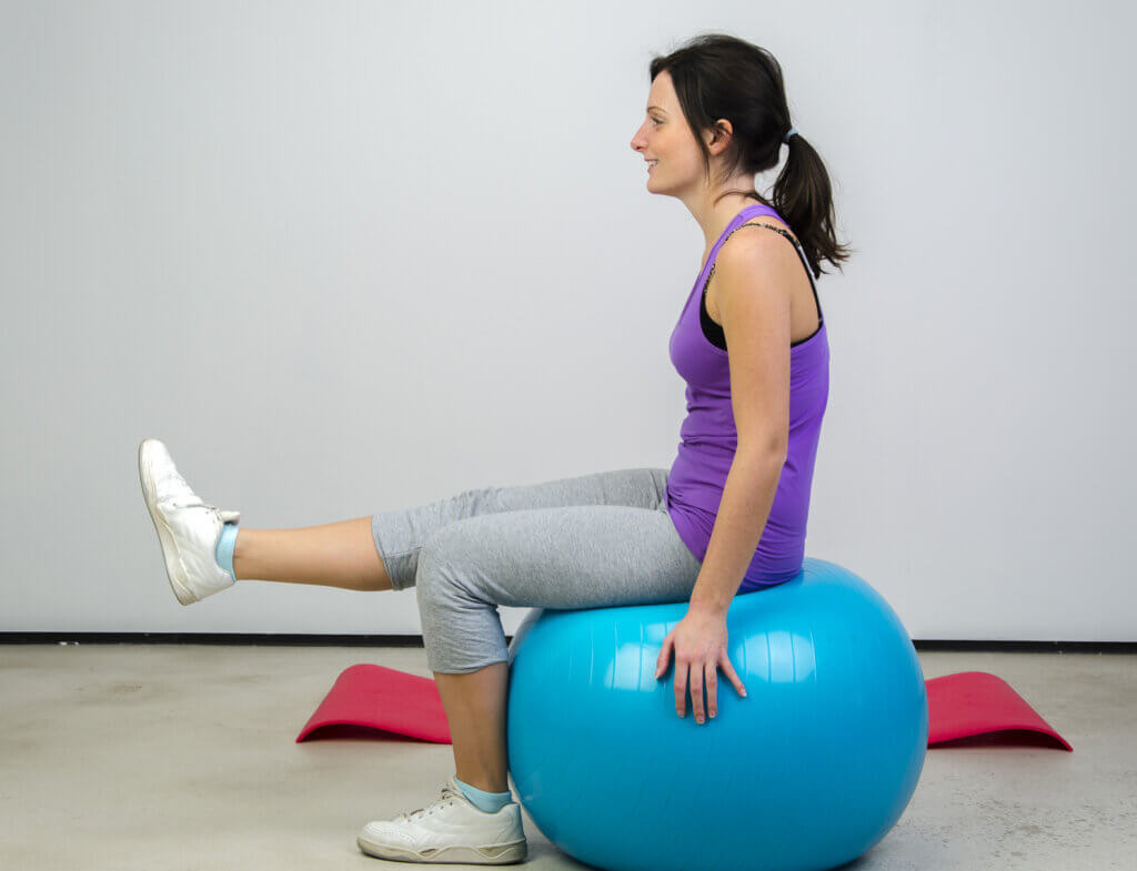 Frau sitzt auf Gymnastikball