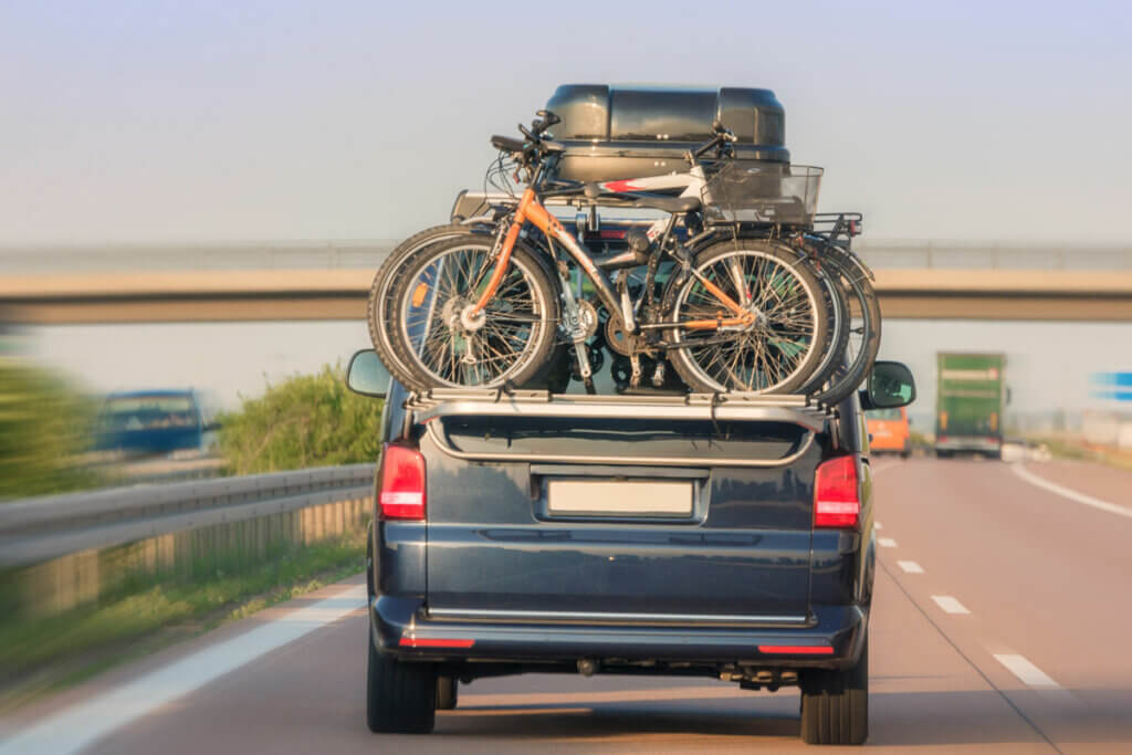 Auto mit Dachgepaeckktraeger und Fahrradhalterung faehrt auf Autobahn