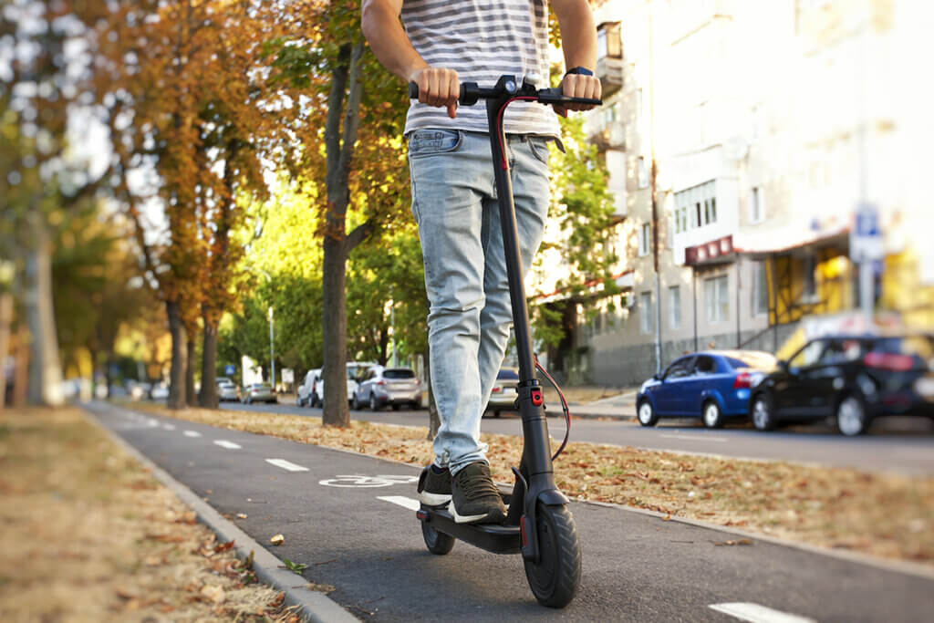 Mann faehrt auf E-Scooter durch Stadt