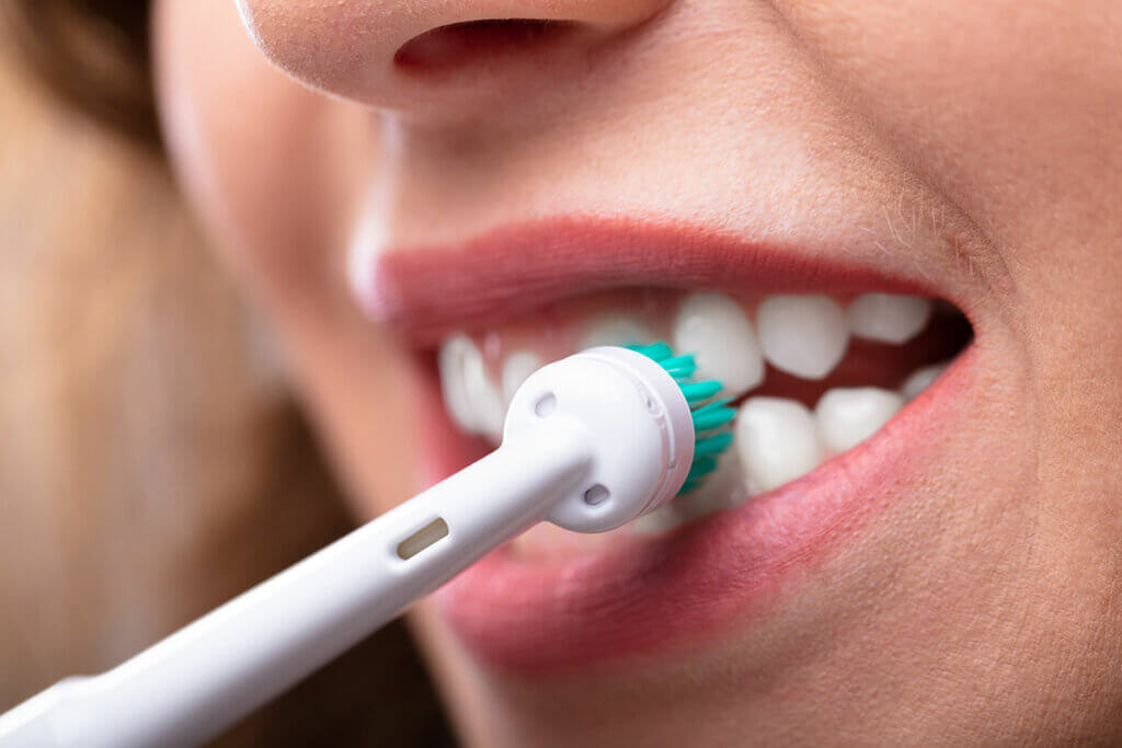 Frau putzt sich ihre Zaehne mit einer elektrischen Zahnbuerste