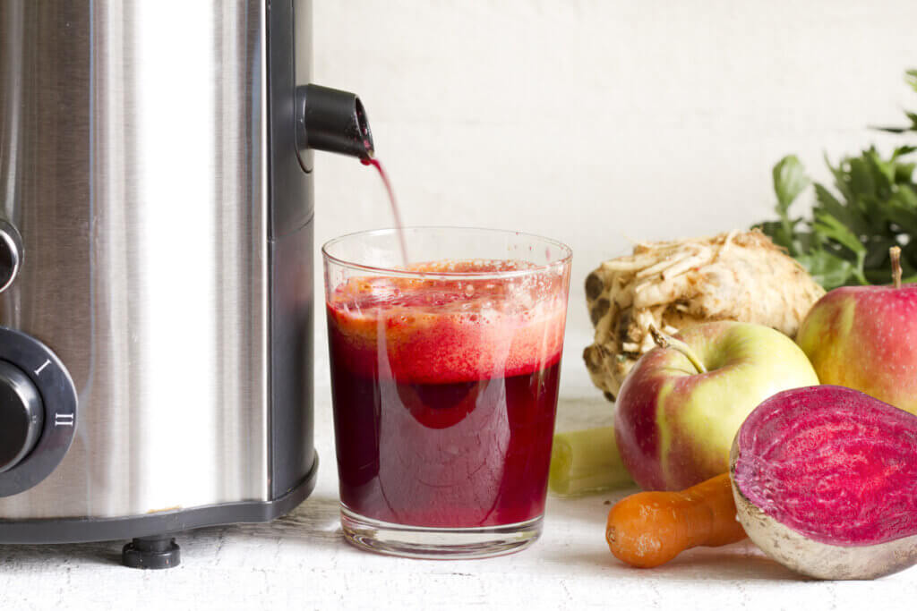 Saft fließt aus Entsafter in Glas