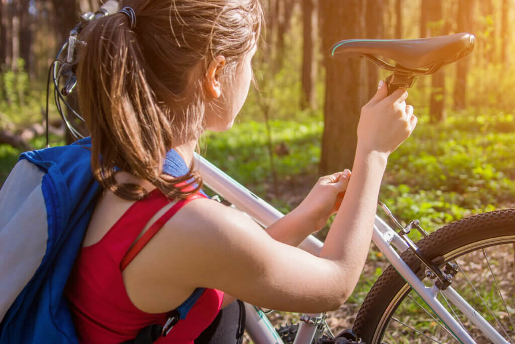Junge Frau stellt ihren Fahrradsattel im Wald ein