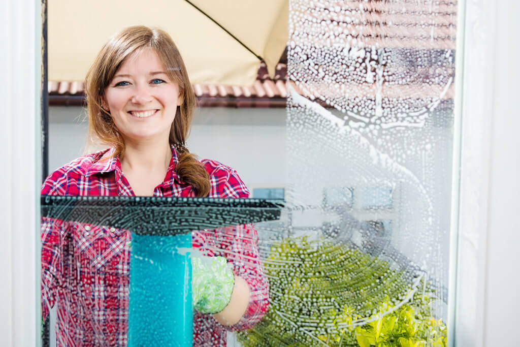 Foto einer Frau in kariertem Hemd, die ihr Fenster saugt