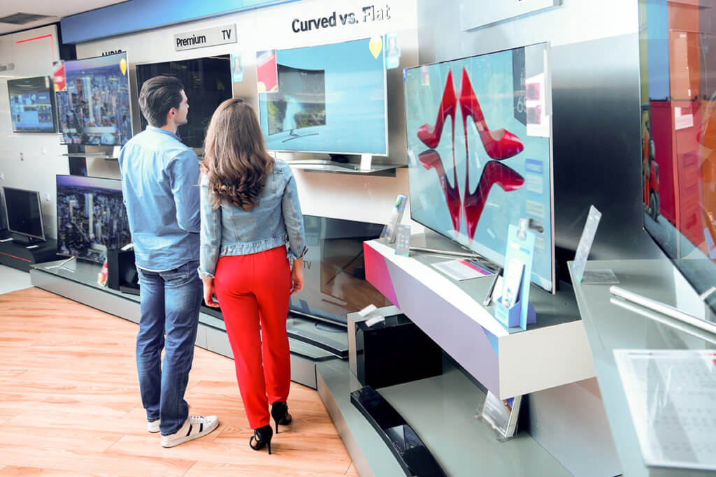 Paar begutachtet Fernseher in Geschaeft