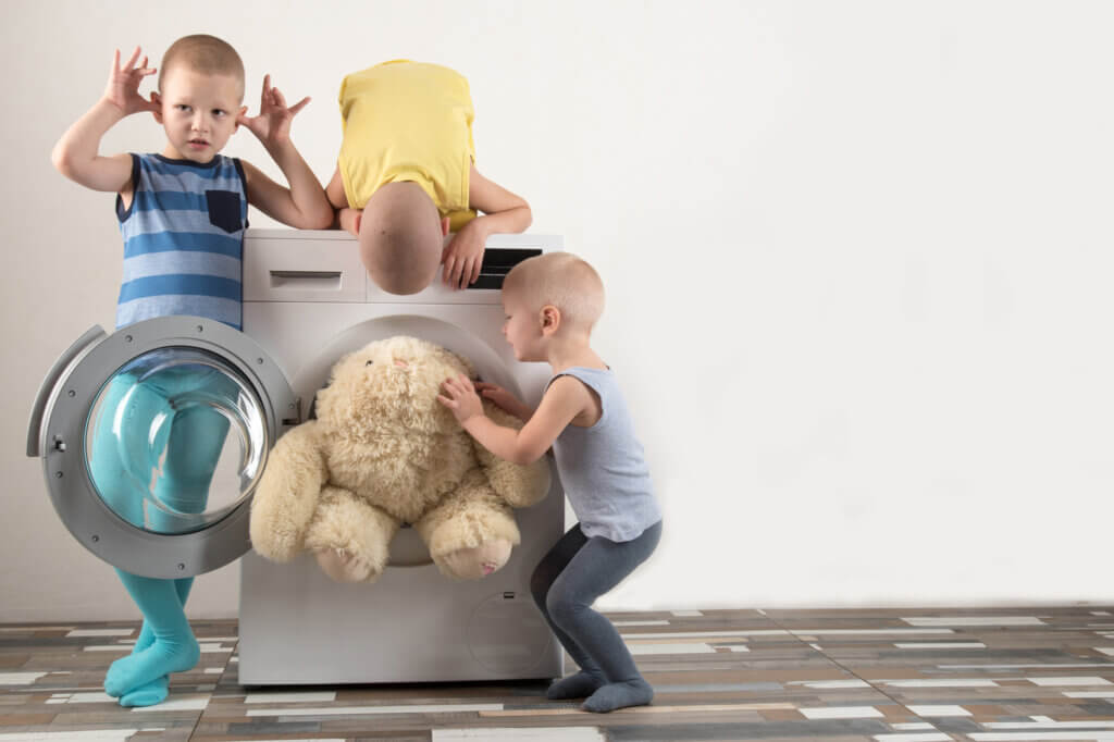 3 Kinder spielen mit Waschmaschine