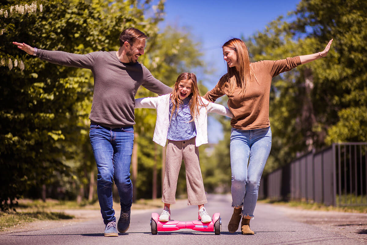 Eltern stuetzen Kind auf Hoverboard