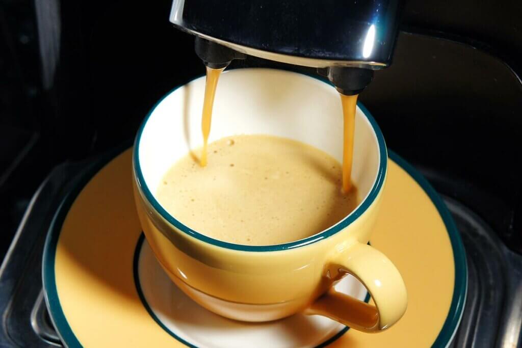 Kaffeepadmaschine-Close-up von Espressotasse, die mit Kaffee gefuellt wird