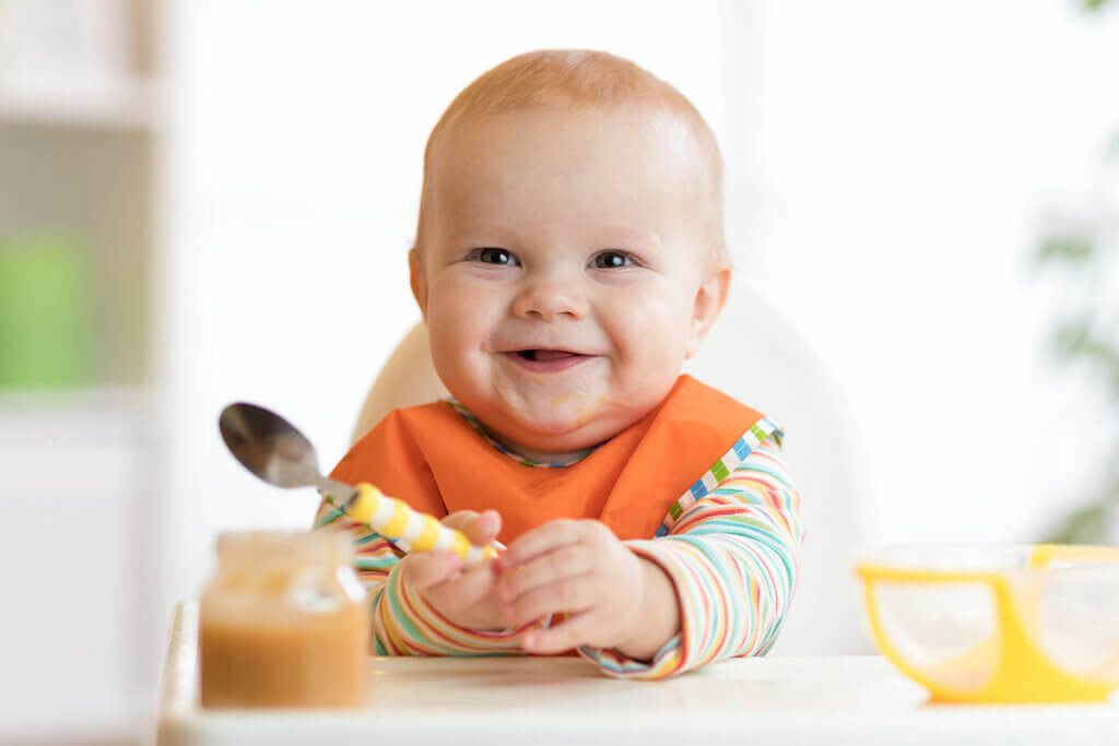 Baby mit Löffel in Hochstuhl