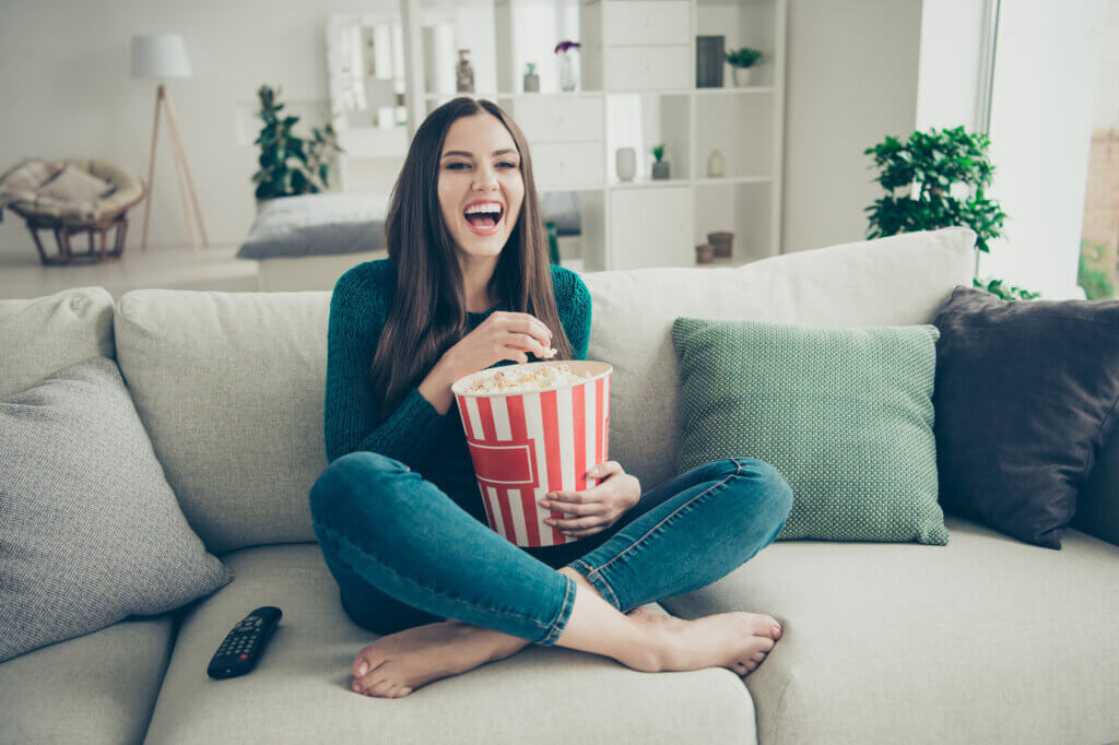 frau guckt einen film lacht udn isst popcorn