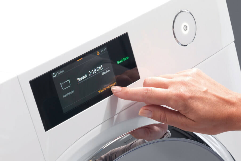 Person bedient Display einer Waschmaschine