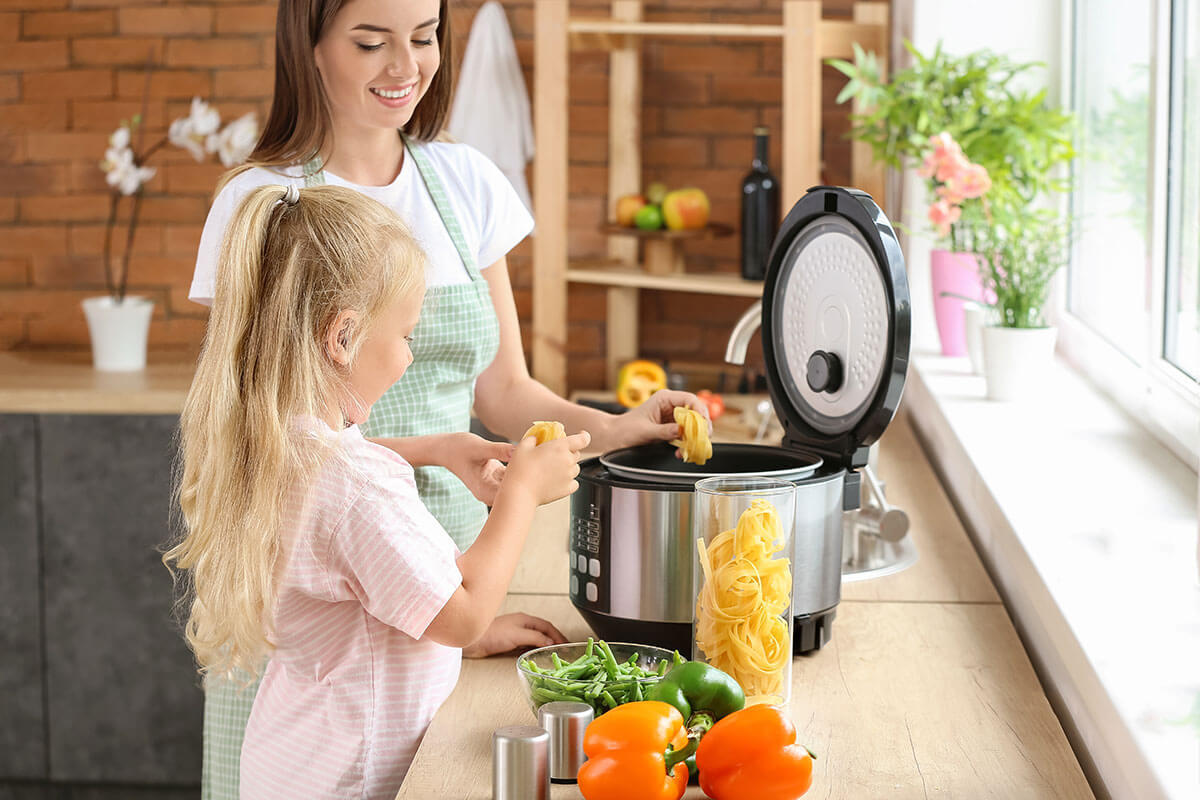 Mutter und Kind kochen mit Multikocher
