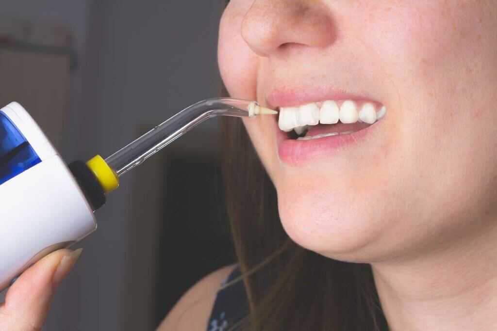 Frau nutzt Munddusche fuer die Reinigung der Zahnzwischenraeume