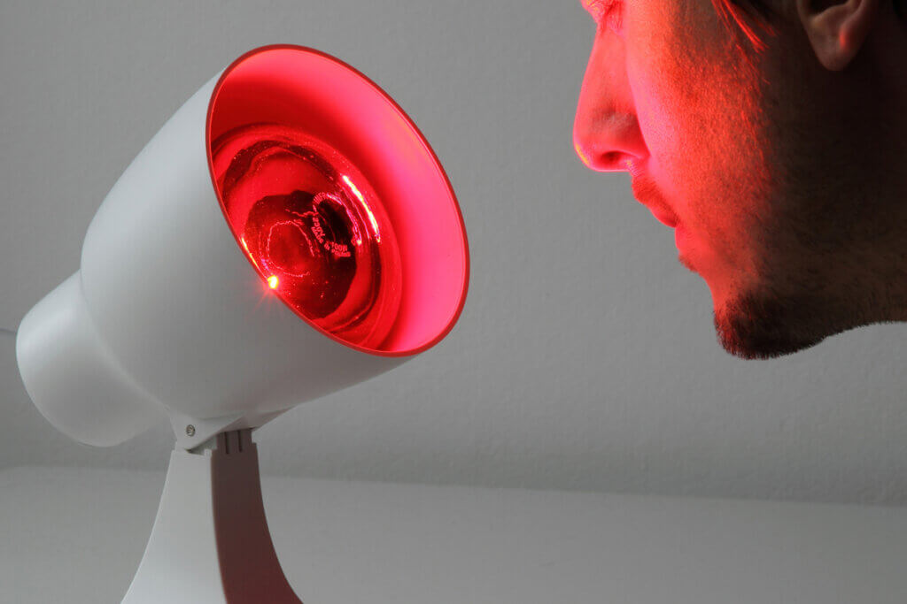 gesicht eines mannes wird von einer rotlichtlampe angestrahlt