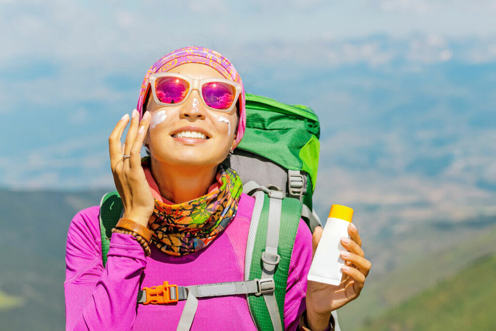 Person cremt sich Gesicht waehrend einer Wanderung ein