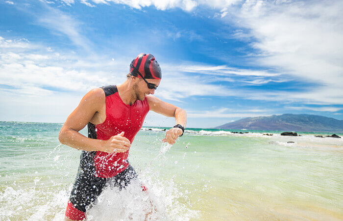 Schwimmer steht im Wasser und schaut auf Sportuhr