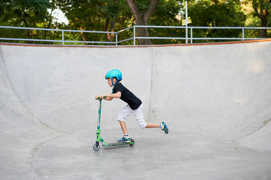 Kind mit Stunt-Scooter im Skatepark