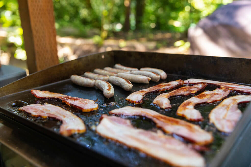 bratwürste und speck werden gegrillt