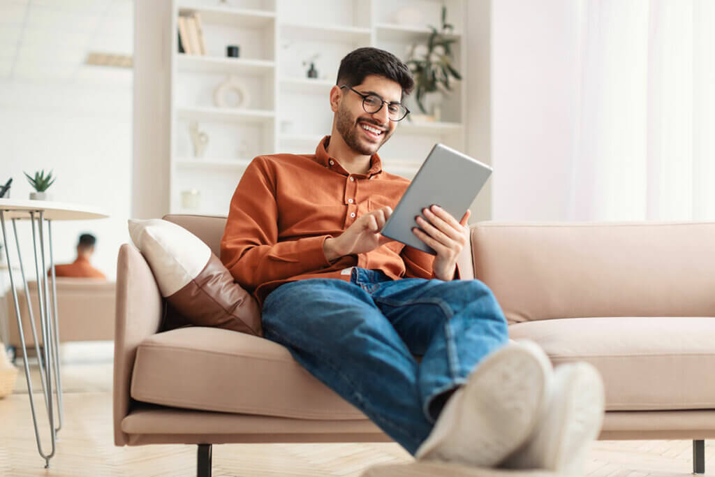 Mann nutzt Tablet auf Sofa