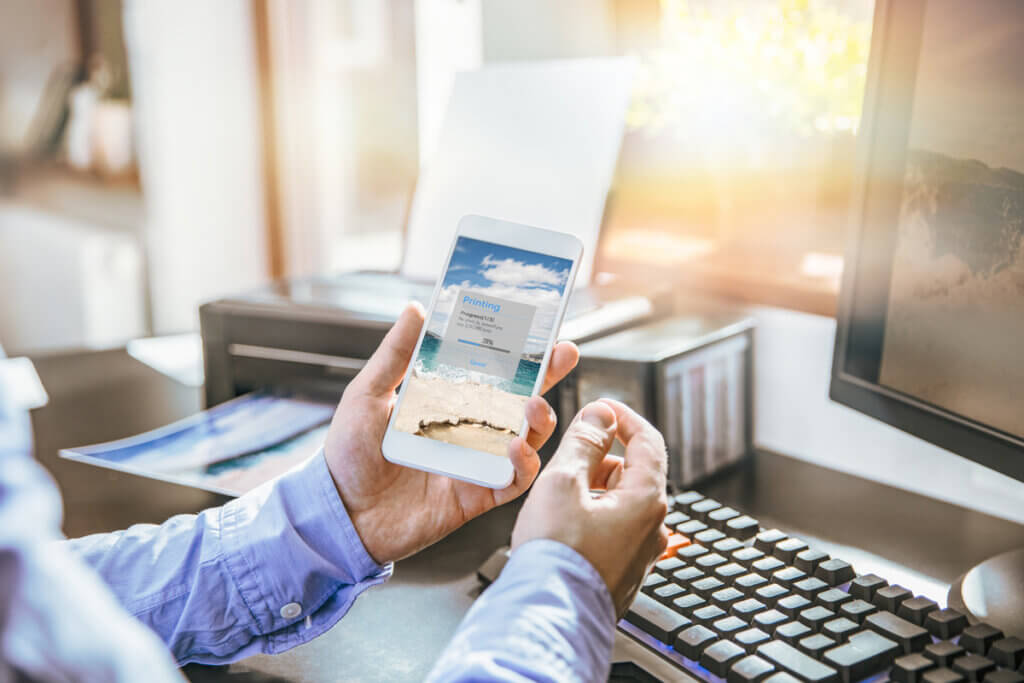 pereson druckt foto aus, nutzt smartphone zur bedienung